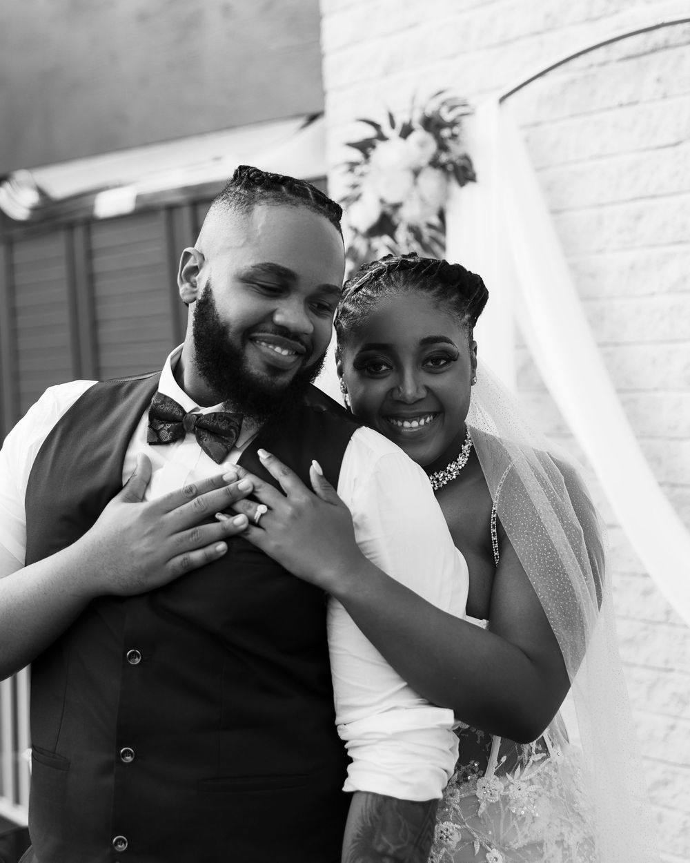A black and white wedding portrait showcasing rings and genuine smiles.