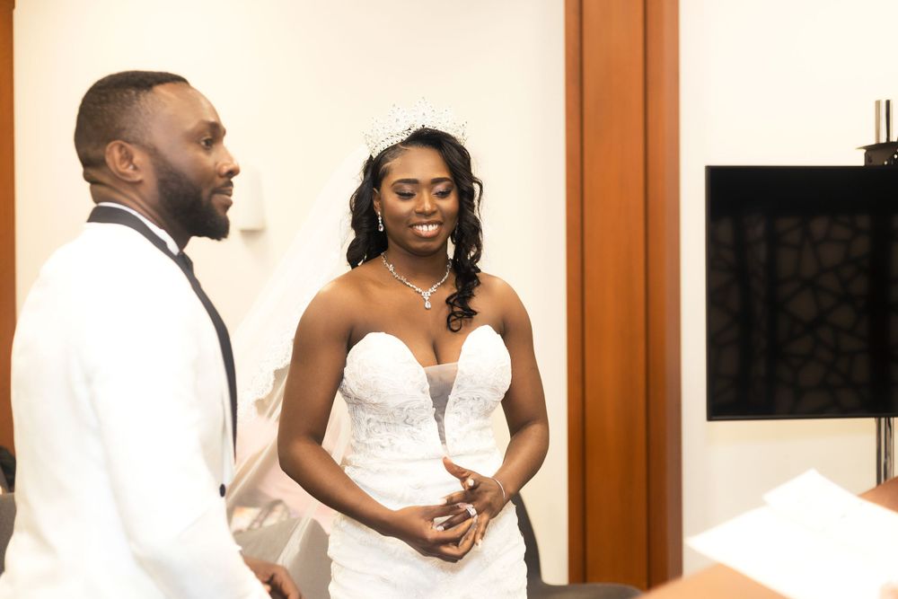 A touching indoor moment between two wedding participants in white formal attire.