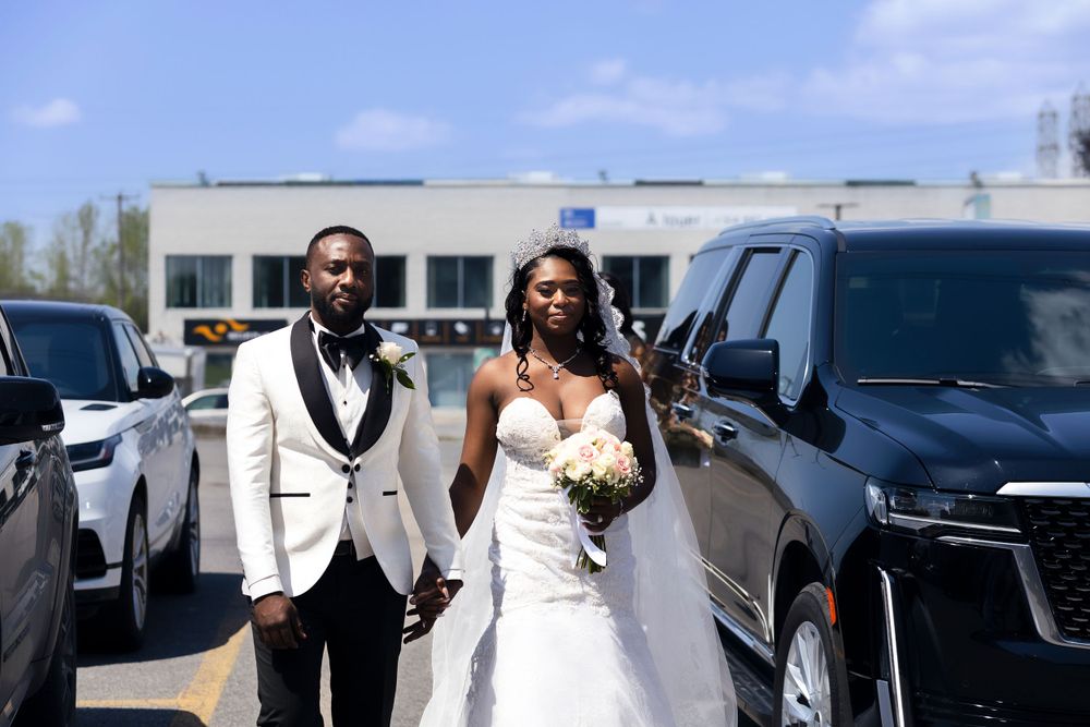 A wedding couple walks through a parking lot on their sunny wedding day.