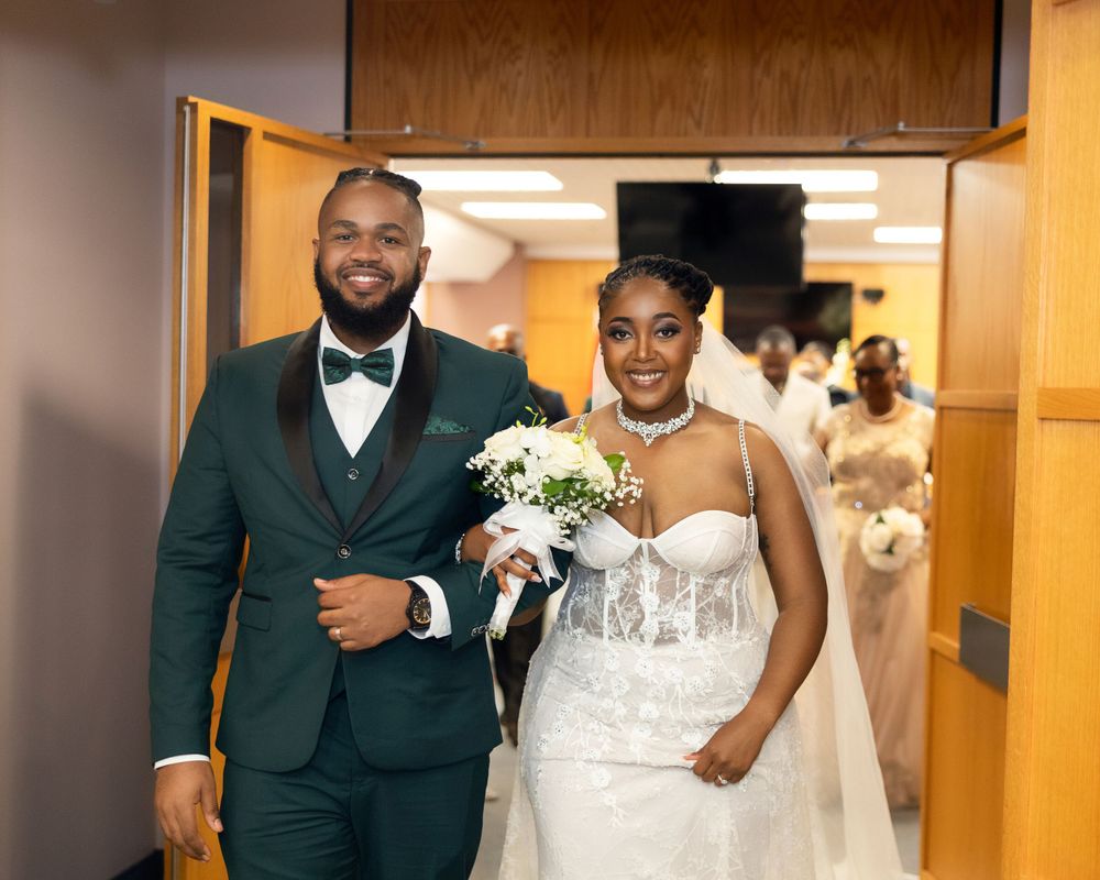 An elegant wedding entrance with a green suit and white gown.