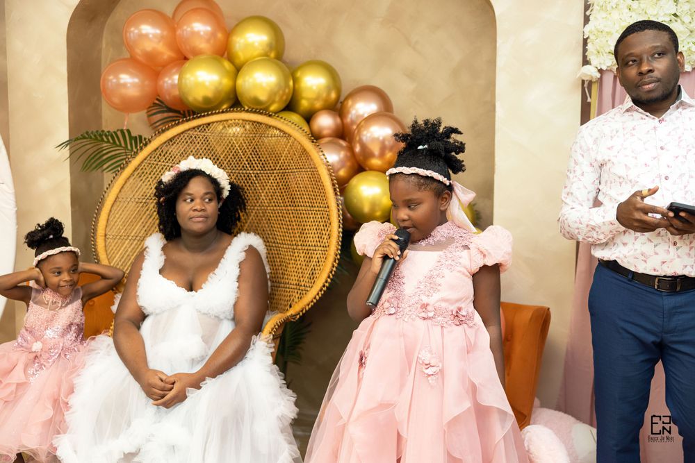 Wedding celebration with whimsical balloon arch featuring orange and gold balloons and a decorative wicker peacock chair.
