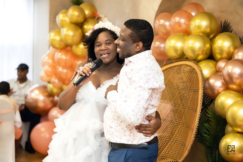 Romantic moment captured during wedding celebration with gold and orange balloon backdrop.