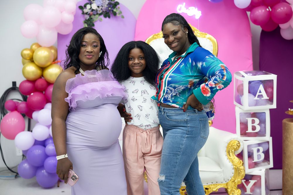 Baby shower gathering with decorative ABC blocks and pink balloon arrangements.