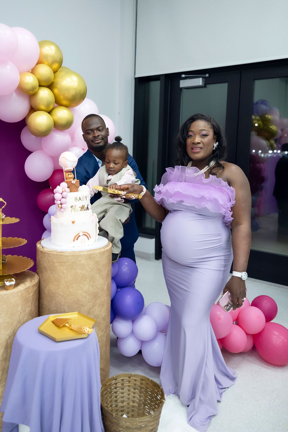 Baby shower celebration with elegant cake display and colorful balloon arrangements.