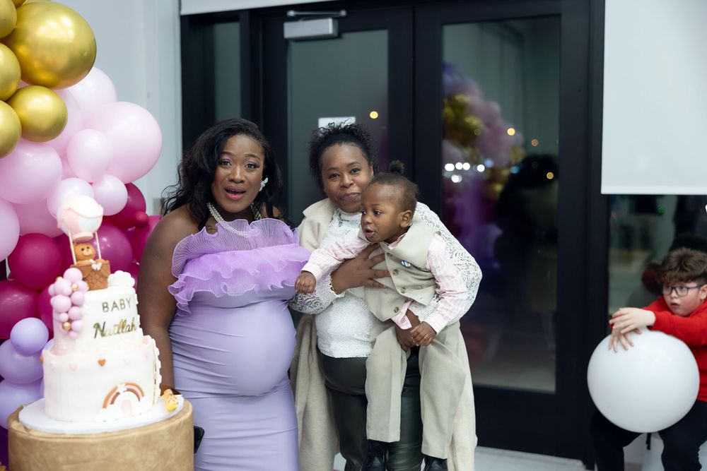 Family moment at baby shower with tiered cake and festive balloon decorations.