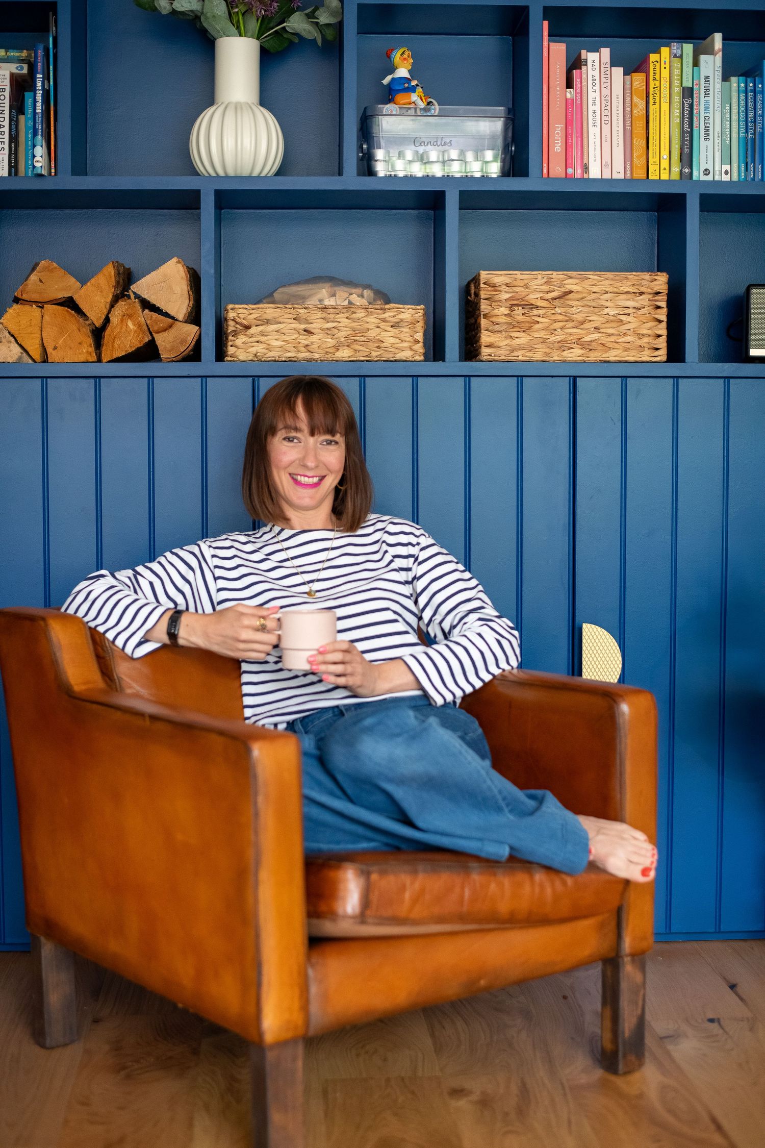 Casual scene with striped shirt against blue built-in shelving filled with books and decor.