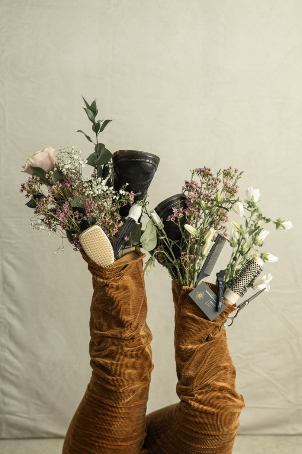 A series of brown vintage-style suede boots filled with delicate wildflowers and greenery against a light background.