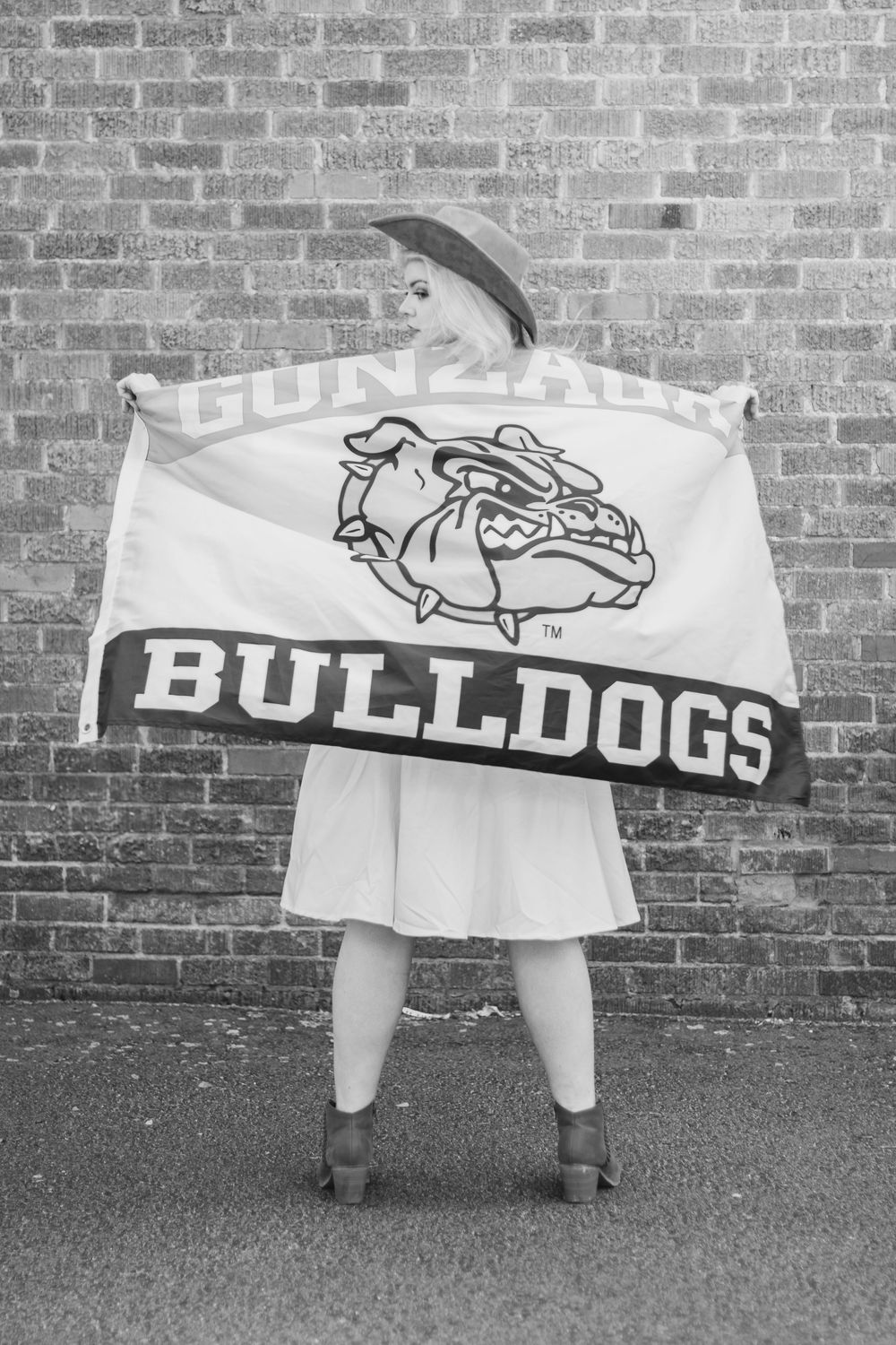 Woman posed with Gonzaga University Bulldogs flag in front of a brick wall in the Garland, Spokane, WA.