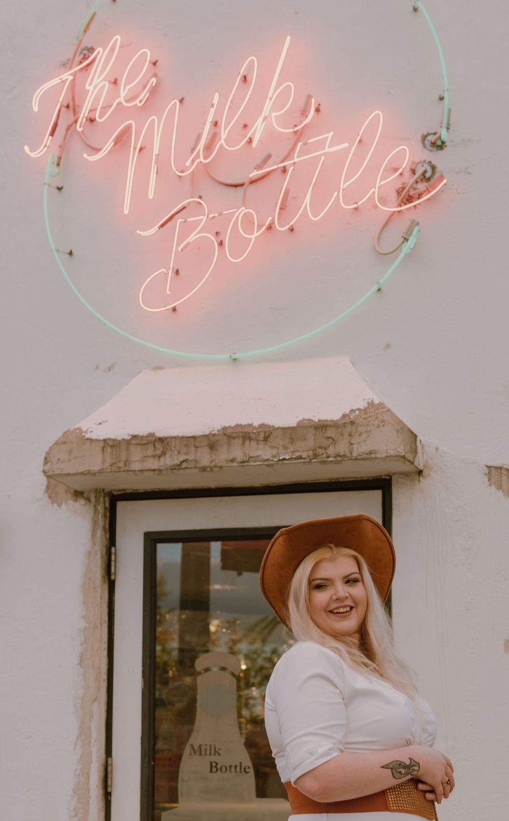 Woman in country style outfit with cowgirl hat posed at The Milk Bottle, Spokane, Washington.
