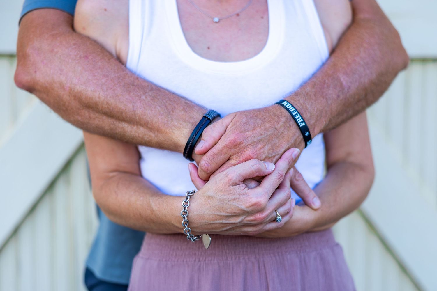 Close-up of hands and wrists wearing layered beaded bracelets in neutral colors.