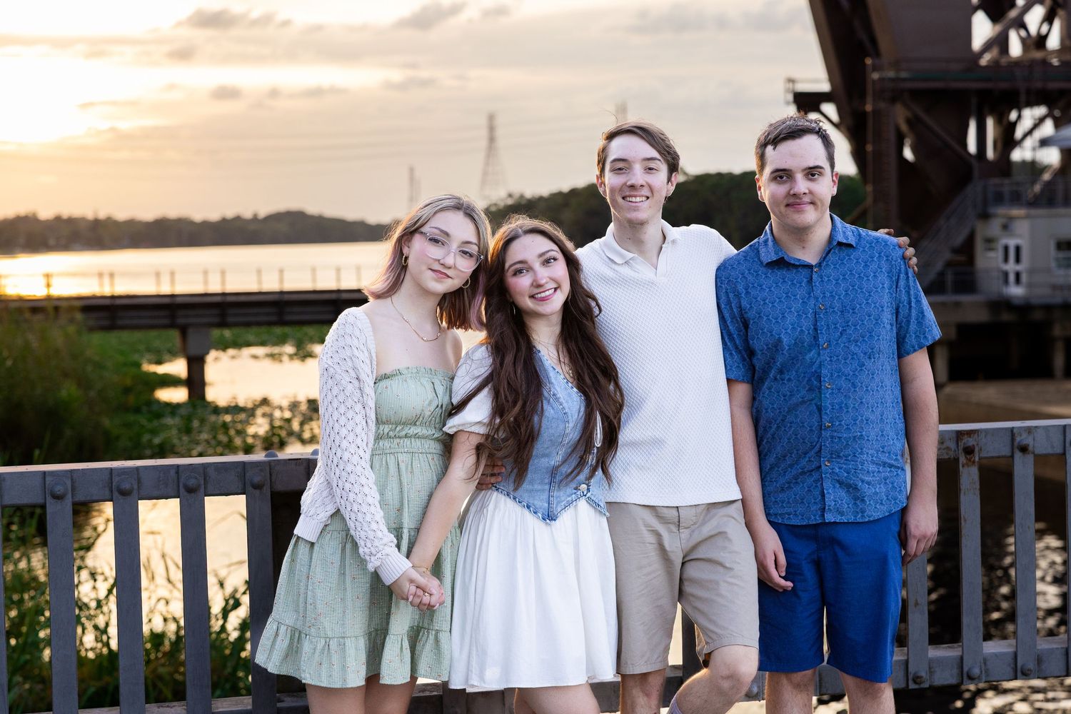 Four people smile and laugh together during a casual outdoor family photo session at sunset.