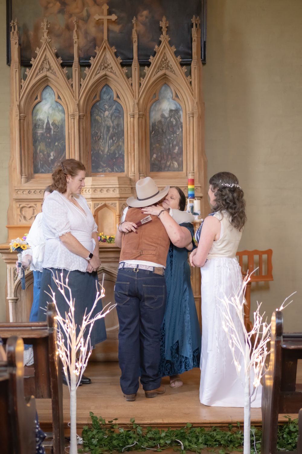 A wedding ceremony takes place inside a chapel with ornate gothic architecture and decorative lighted branches.