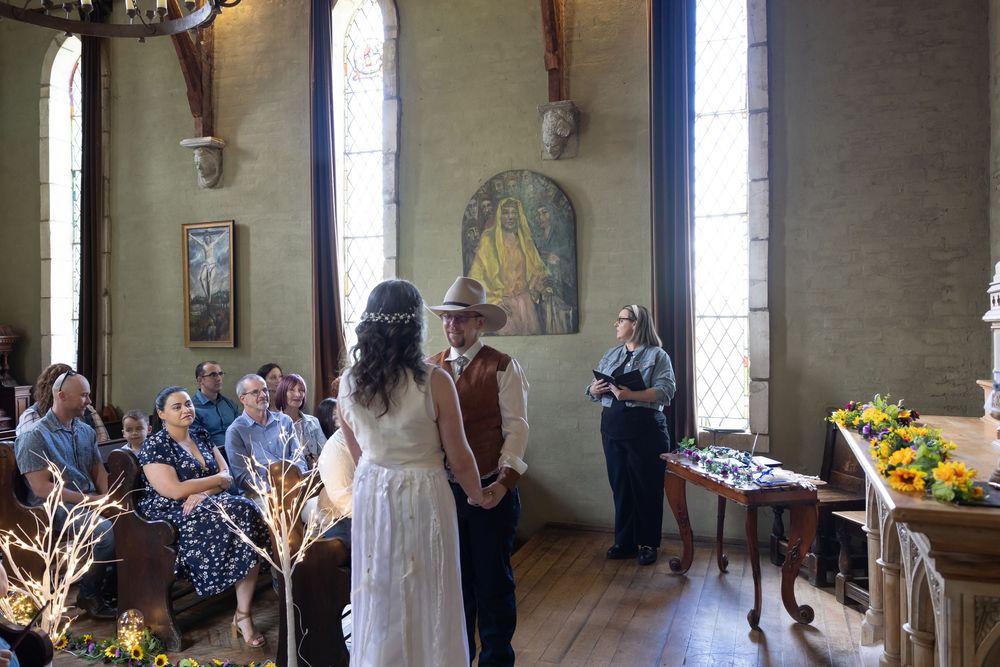Panoramic view of guests socializing in a rustic interior room with high windows and stone walls.
