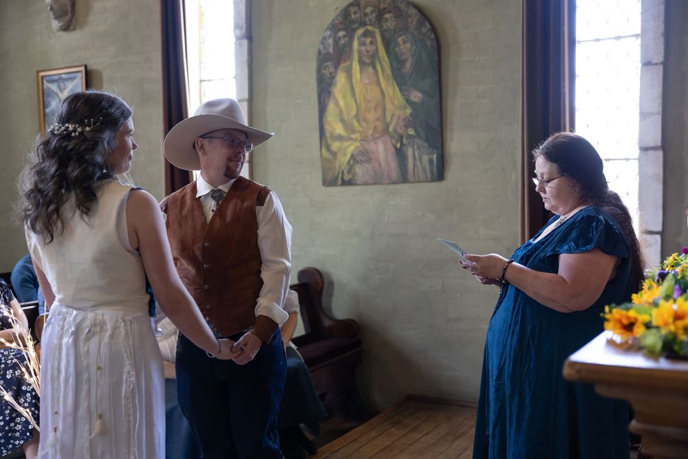 A group of wedding guests socializing and mingling in a rustic venue during a celebration.