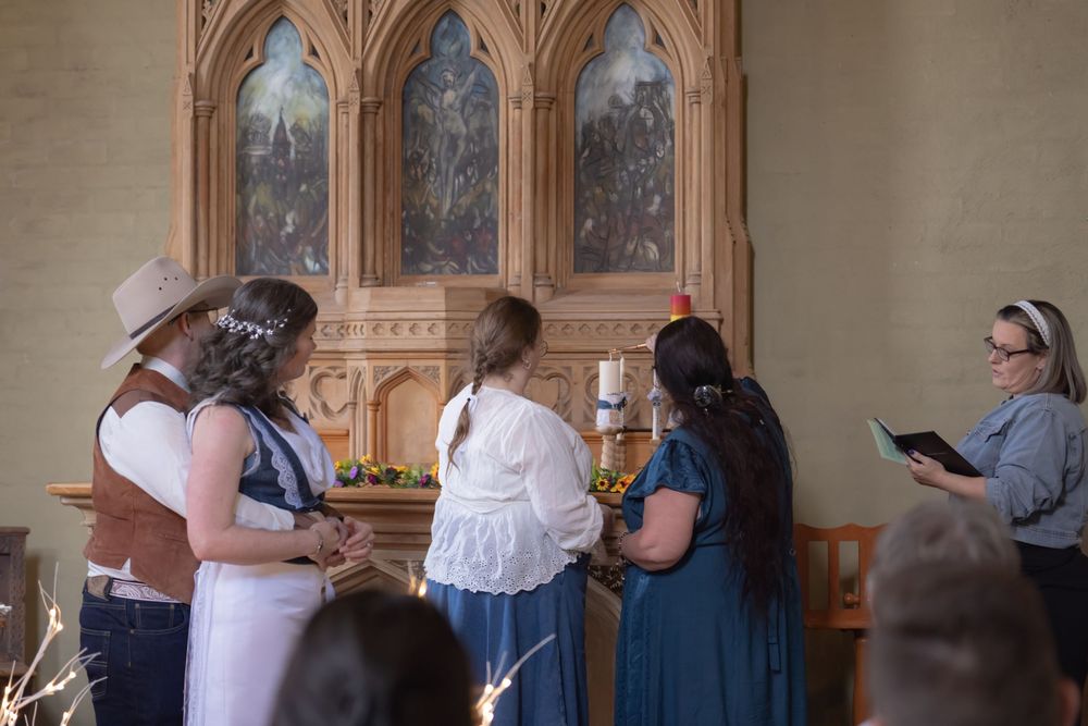 People stand in an ornate room with Gothic style arched windows and architectural details during a guided tour.