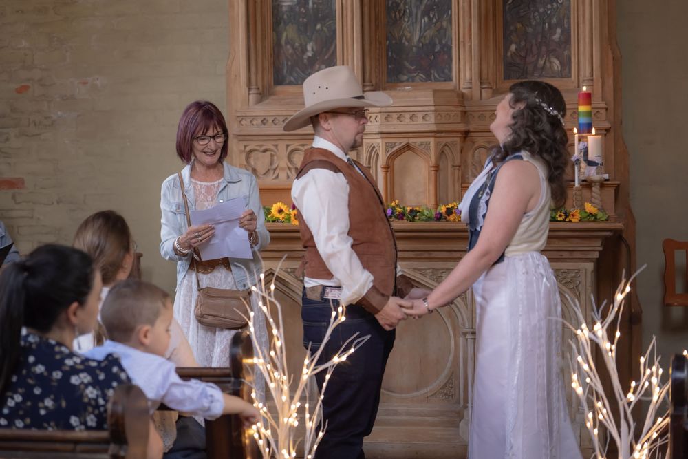 A group dances in white dresses around a wedding sparkler during an indoor celebration.