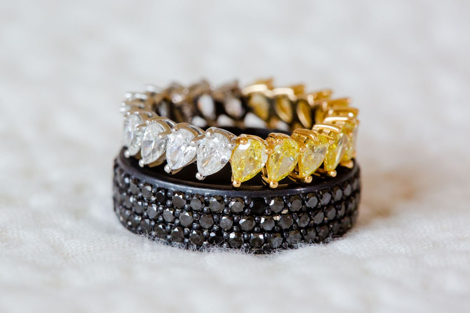 Two elegant wedding rings featuring black diamonds and mixed metal designs on light textured background.