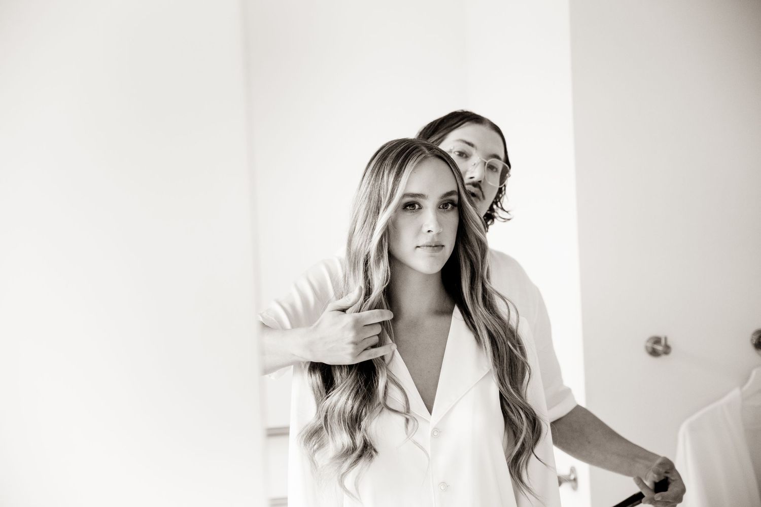 Getting ready moment captured in bright white room with mirror reflection.