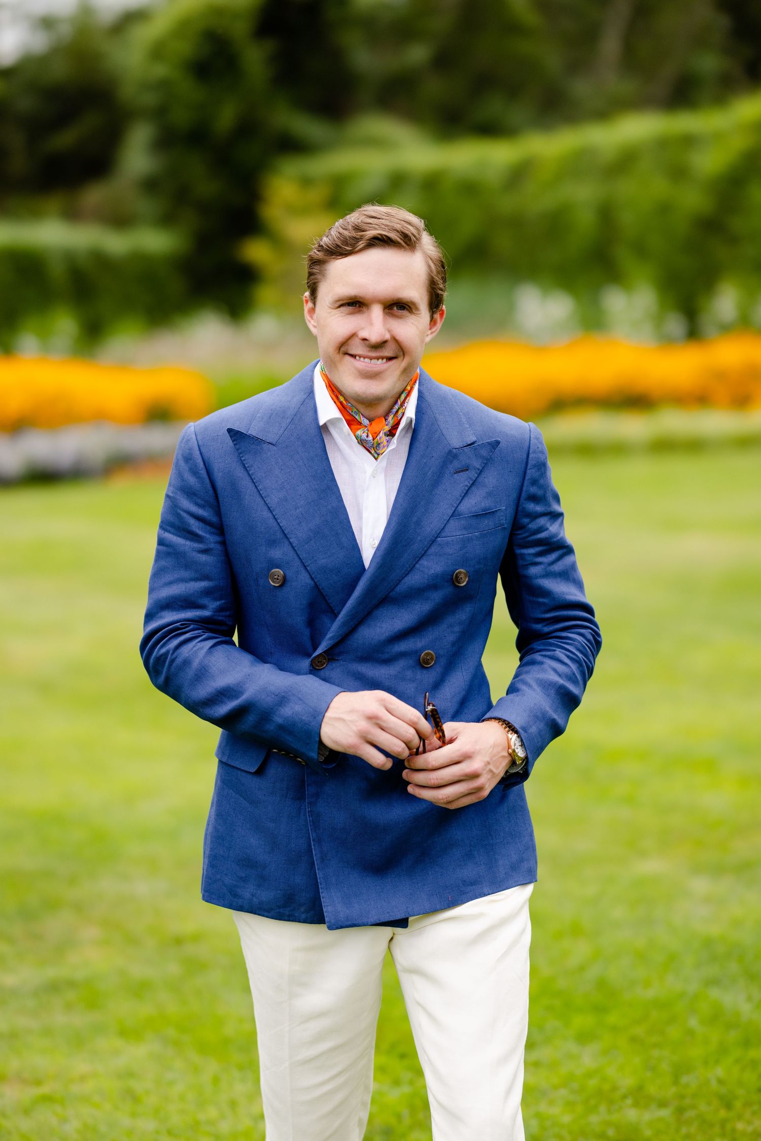 Stylish outfit featuring navy double-breasted blazer and white pants in garden setting.