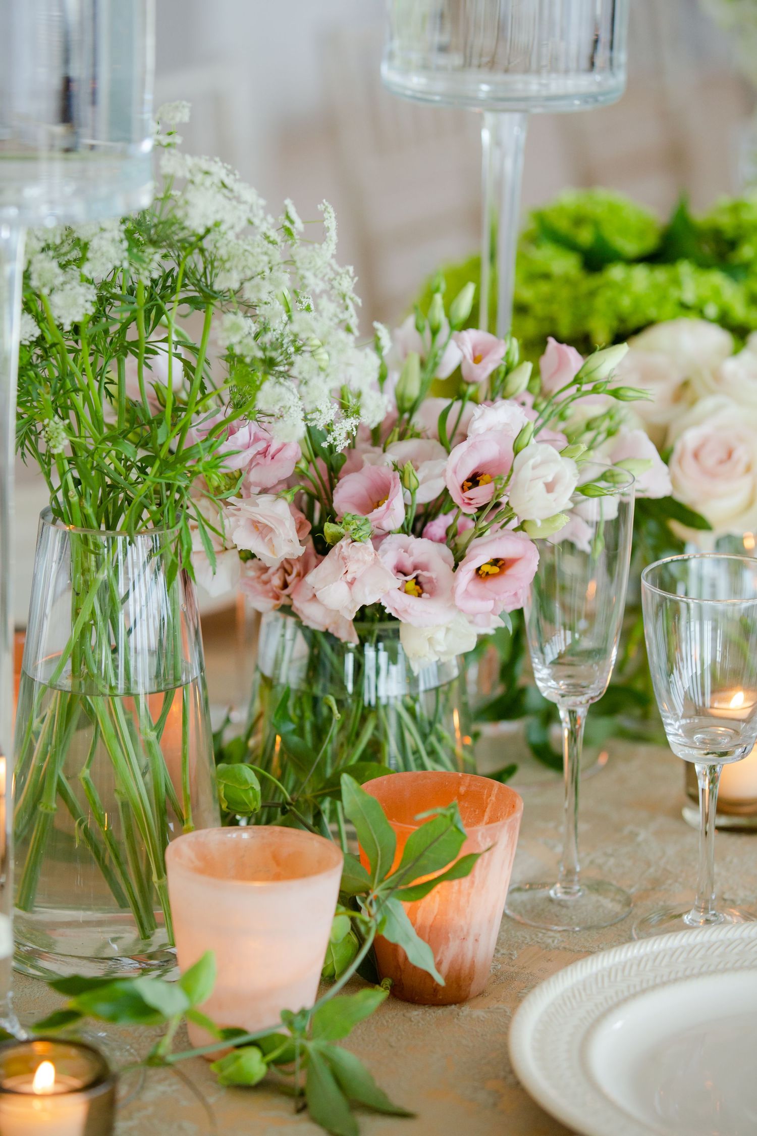 Elegant wedding table setting with pink flowers, candles and champagne glasses.