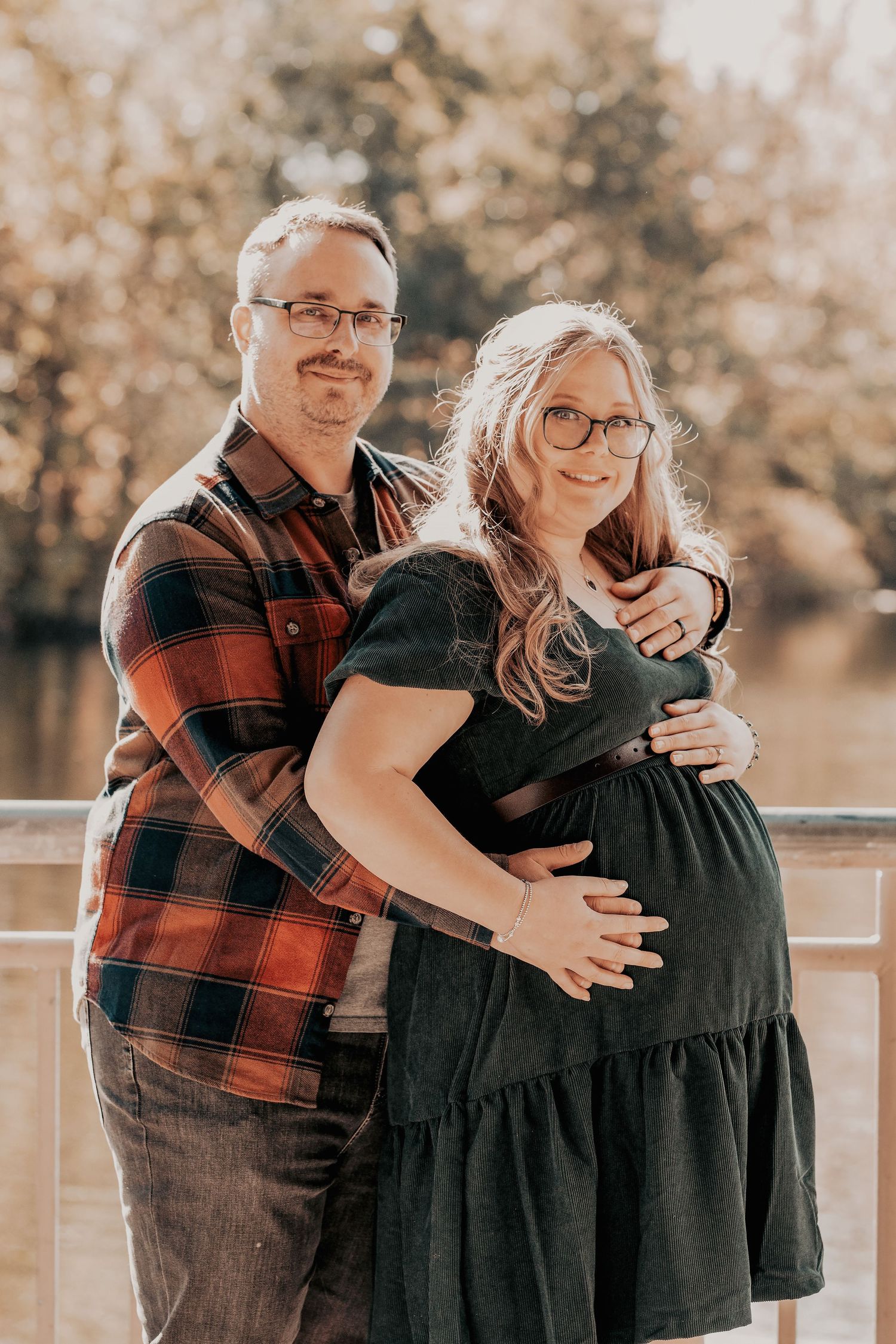 A loving couple embraces in a warm autumn setting wearing black and red plaid while sharing candid, joyful moments.