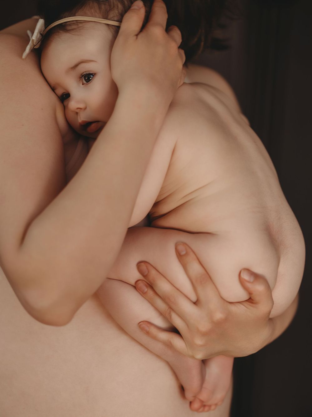 A mother tenderly breastfeeding her baby, captured in a warm, intimate portrait celebrating the bond of motherhood.