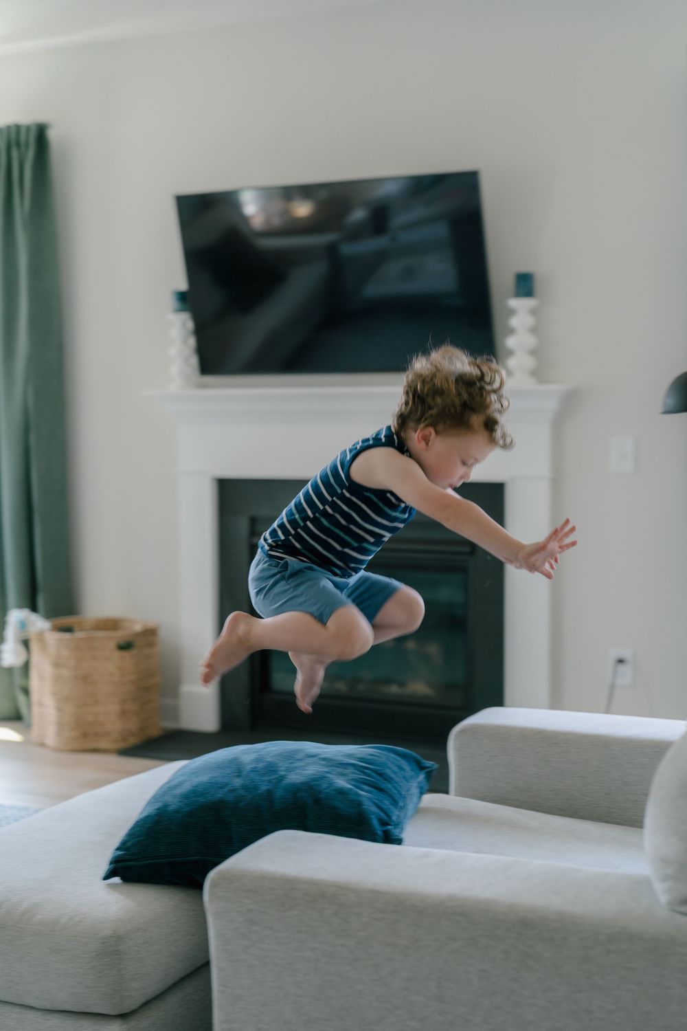 Series of photos showing playful jumping and bouncing motion sequence on a gray couch in a living room at in-home newborn photo session Ohio