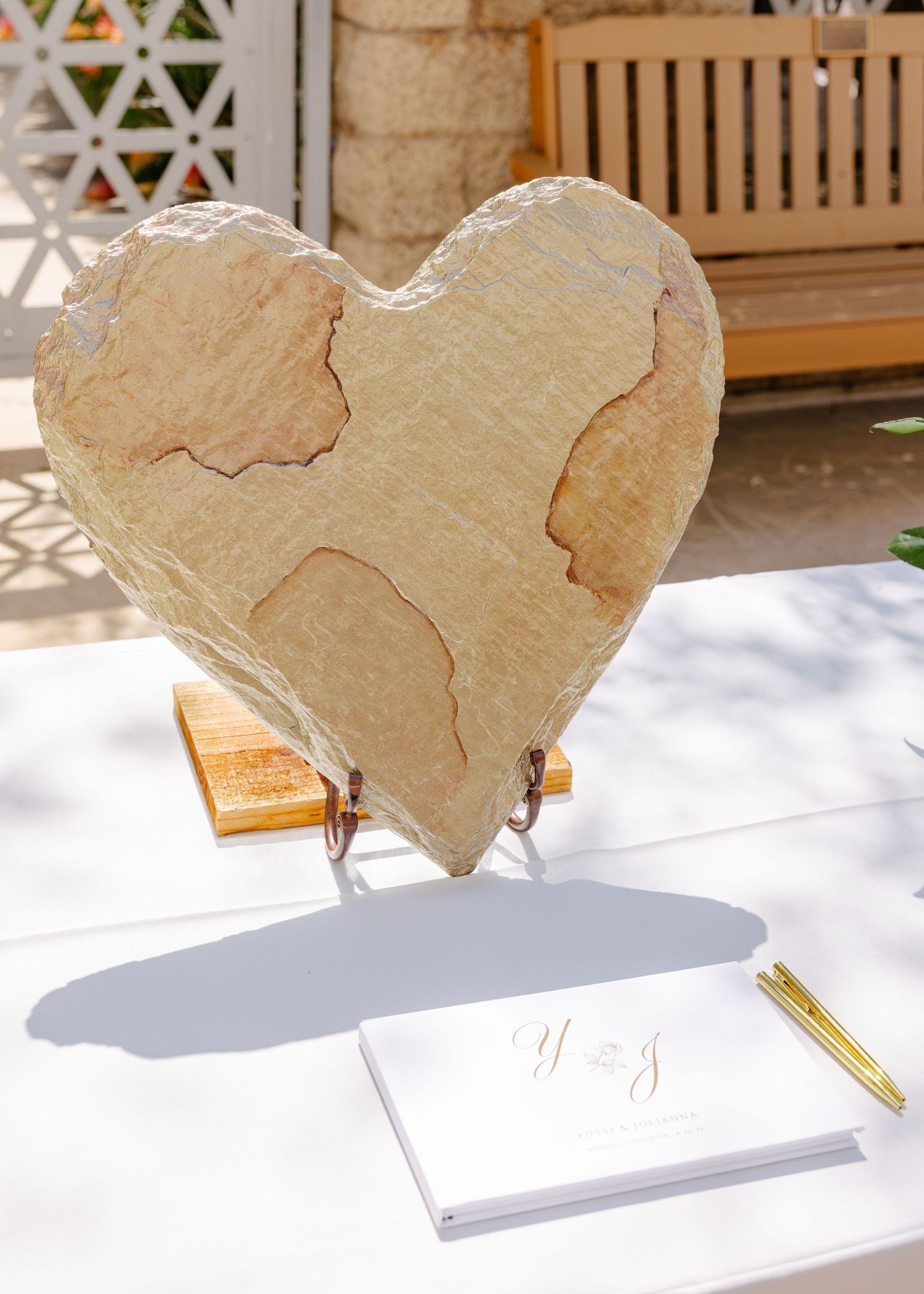 A heart-shaped stone or concrete decorative piece sits on a stand next to a small notepad and pen.