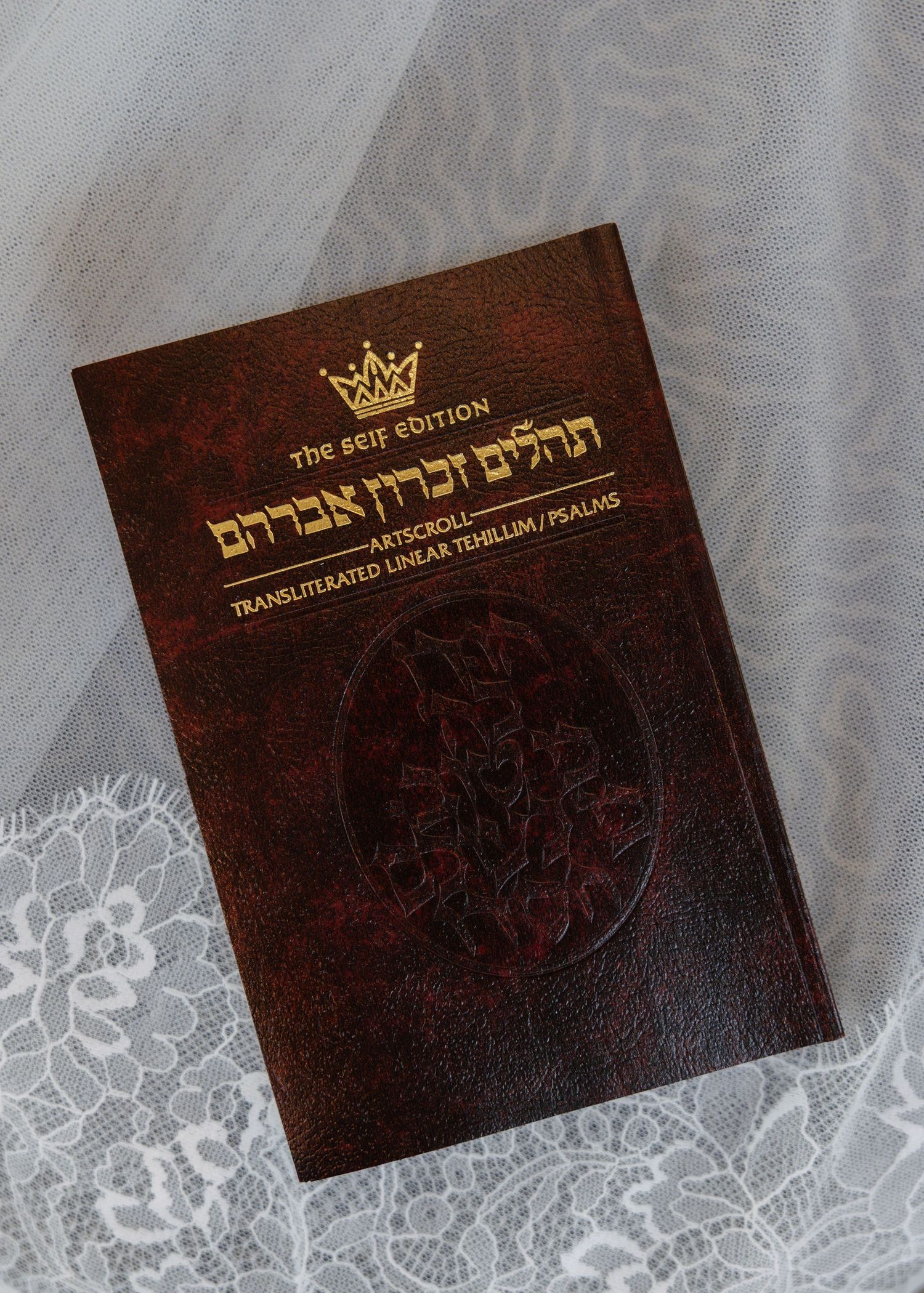 Dark brown leather wedding invitation cards with gold crown emblem and Hebrew text.