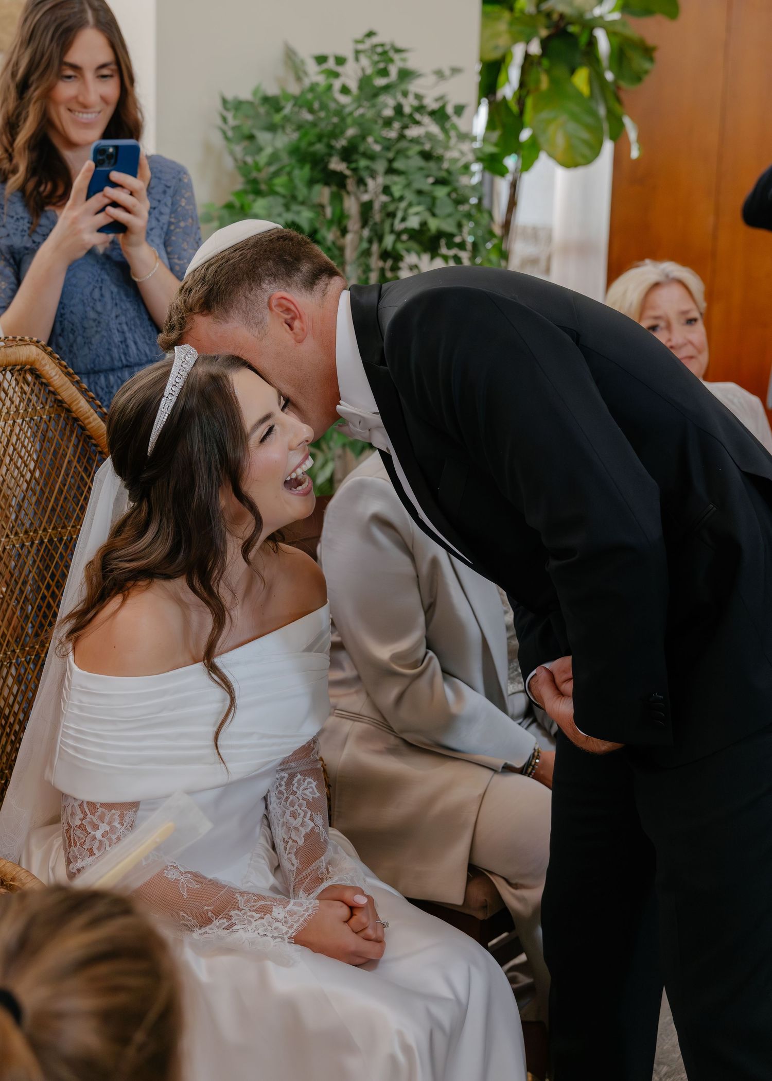 A tender moment captured during a wedding celebration with greenery in the background.