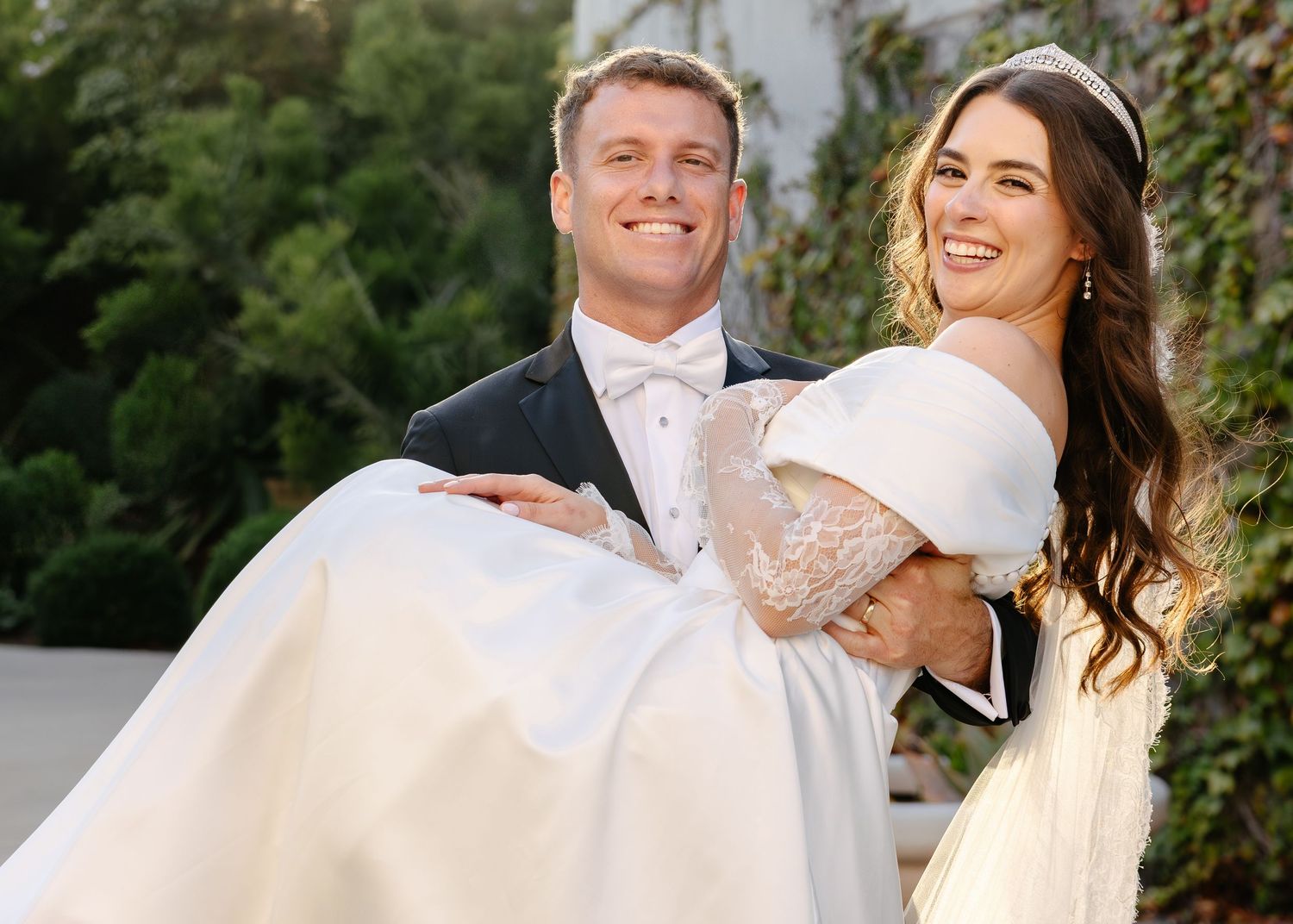 Joyful couple embraces and shares romantic moments while celebrating their wedding day outdoors.