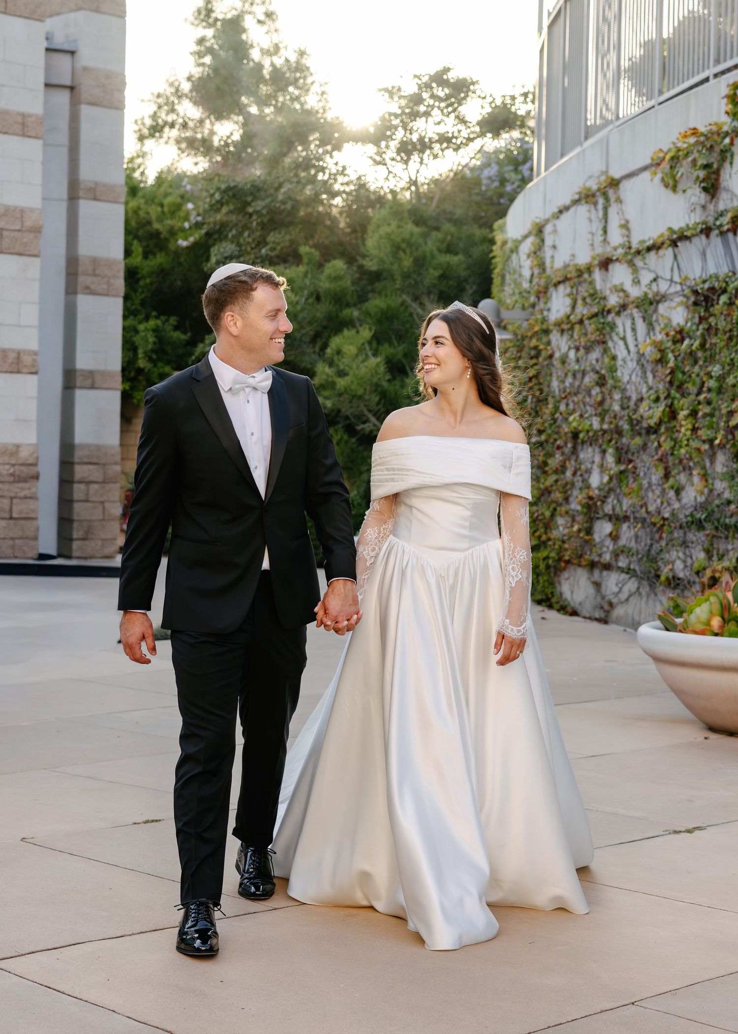 A couple sharing a joyful moment in formal attire during what appears to be a wedding photo session.