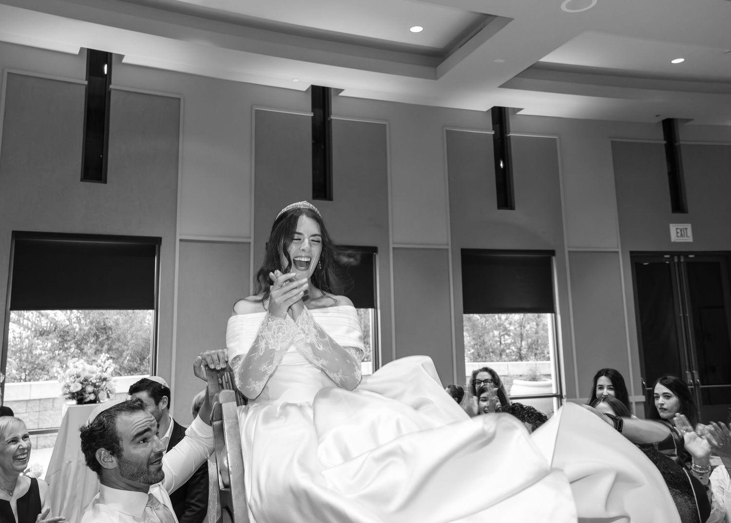 A black and white panoramic sequence showing the joyful celebration and dancing during a wedding reception.