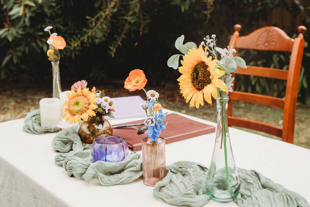 Table decorations feature small glass bottles with sunflowers and peach roses alongside delicate figurine ornaments.