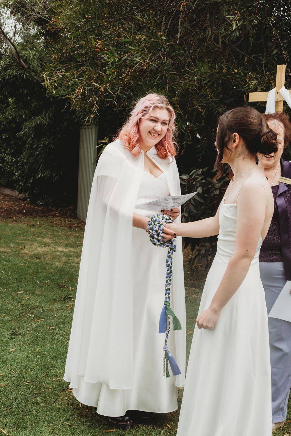 A group gathers outdoors wearing white dresses and interacting playfully at a daytime event.