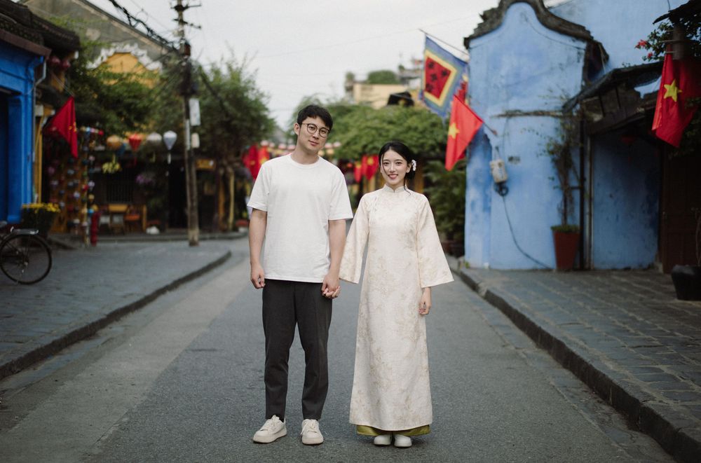 People walk along a charming street decorated with red flags and traditional Asian architecture.