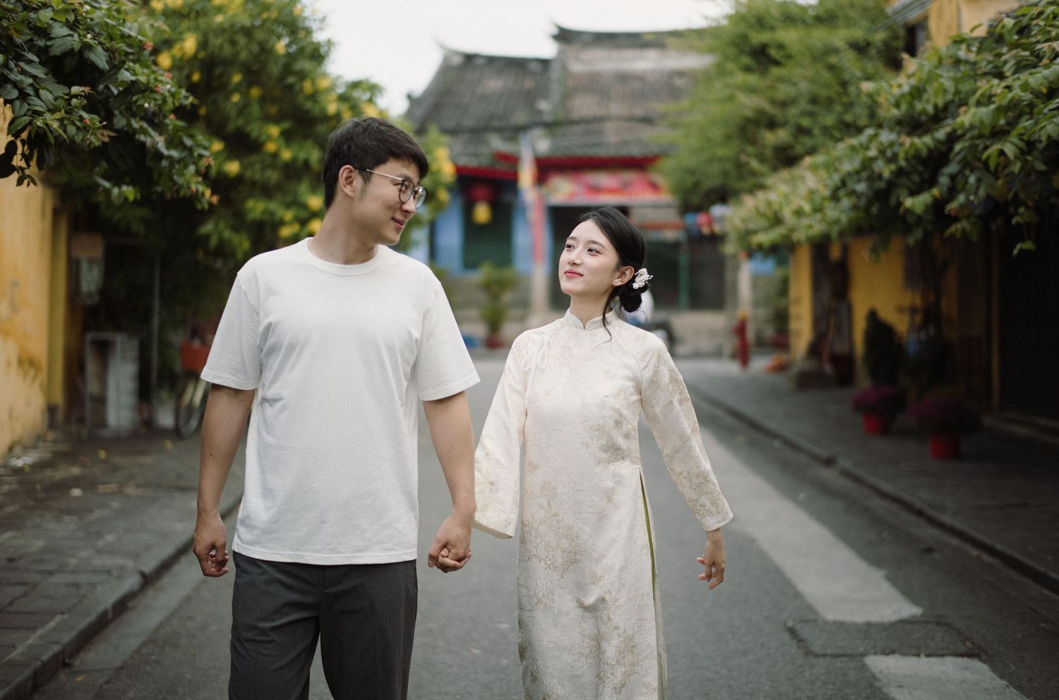 Couple walking hand in hand through a scenic street in an old Asian town.