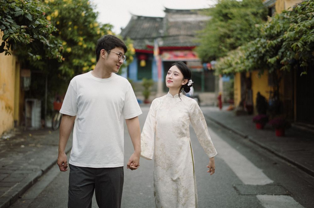 Couple walking hand in hand through a scenic street in an old Asian town.