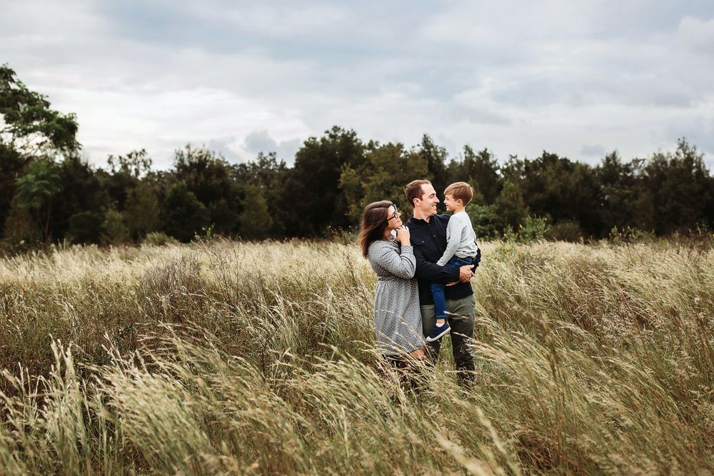Family walking together through a tall grass meadow at golden hour, with long grass swaying in the breeze.