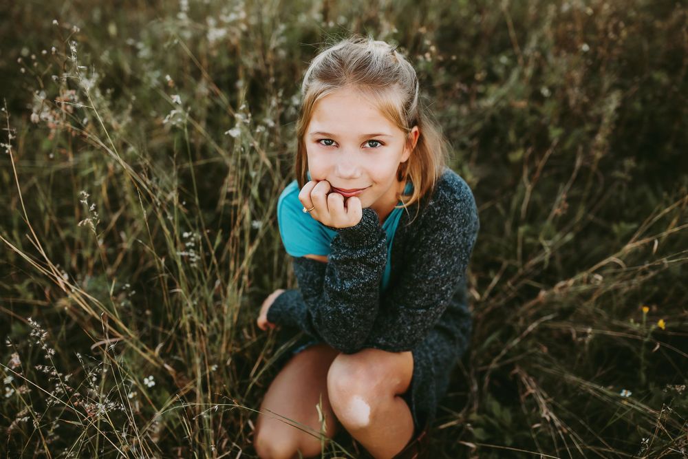 Stylish teal sweater being worn outdoors in tall autumn grasses during golden hour.