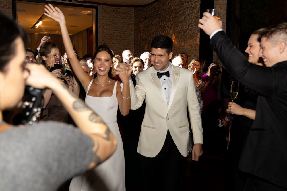 Wedding couple makes their grand entrance at reception as guests applaud and cheer.