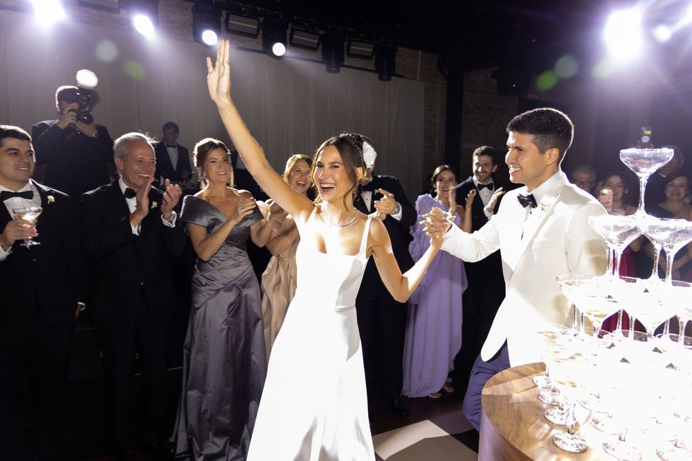Dancing guests enjoy the festive atmosphere of a wedding reception under purple lighting.