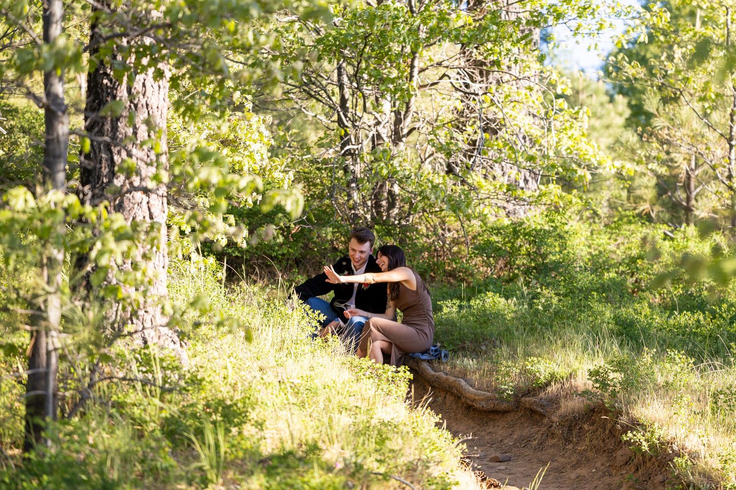 Mountain biker navigates a rocky dirt trail through sunlit forest terrain during an afternoon ride.