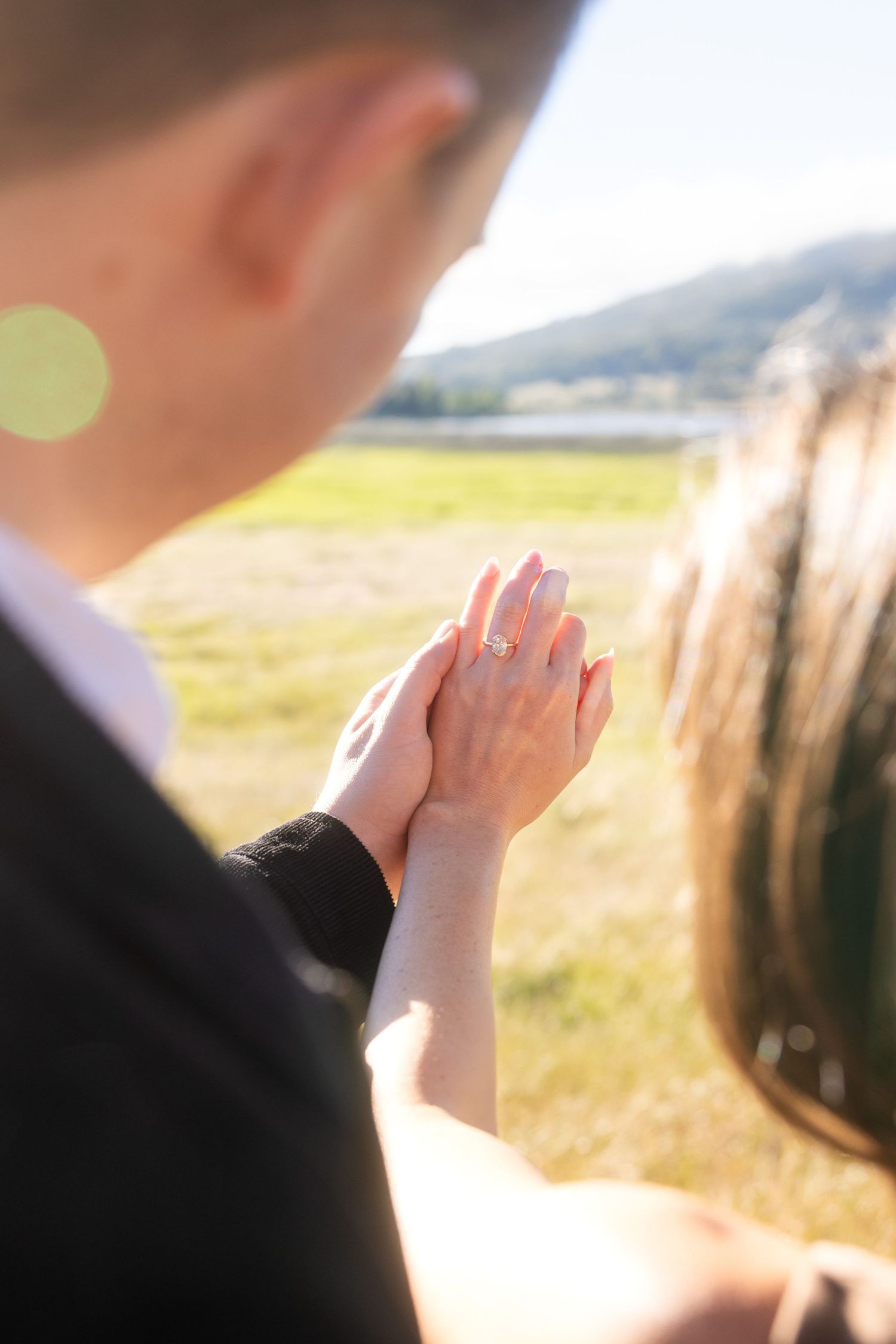 Close-up shot of hands reaching toward a sunlit car window.