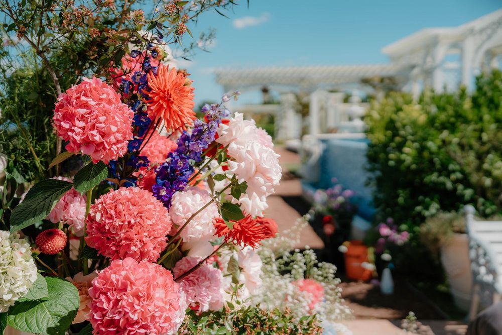 Coral and purple floral arrangements accent a beautiful outdoor wedding venue with classical architecture.