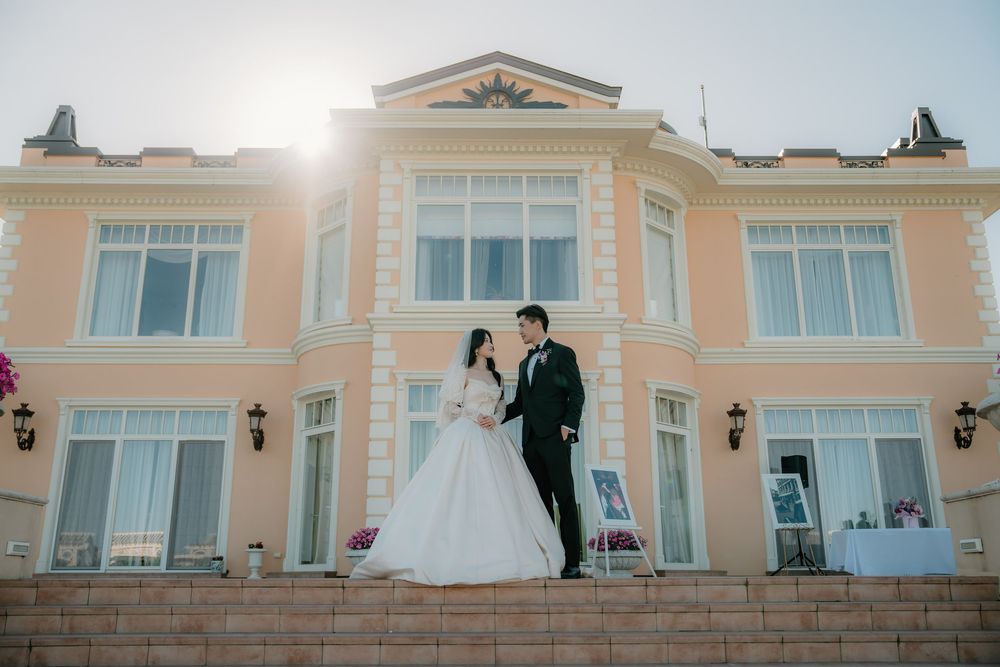 A peach-colored wedding venue building exterior with white trim and outdoor balconies is captured at sunset.