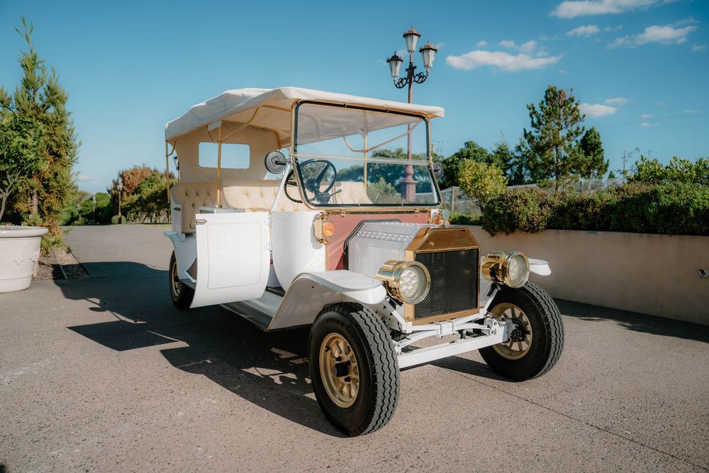 Vintage white convertible cars displayed at an outdoor wedding venue against a mountain backdrop.