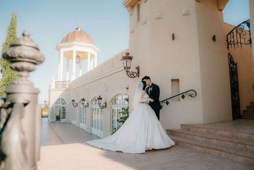 White architectural details and columns frame an elegant Mediterranean-style wedding venue with ornate lighting fixtures.