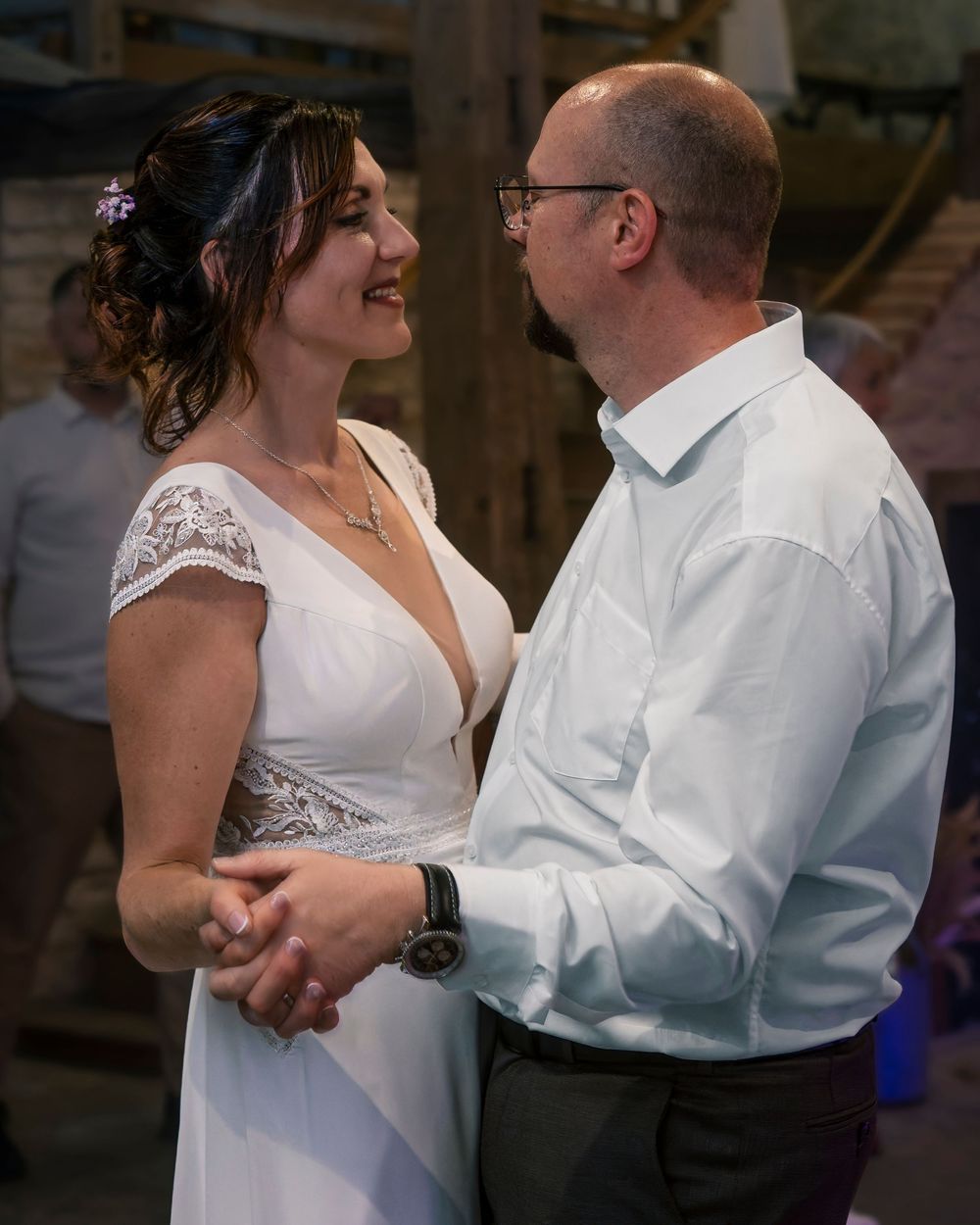 A couple dancing intimately in formal white attire during what appears to be a romantic wedding moment.