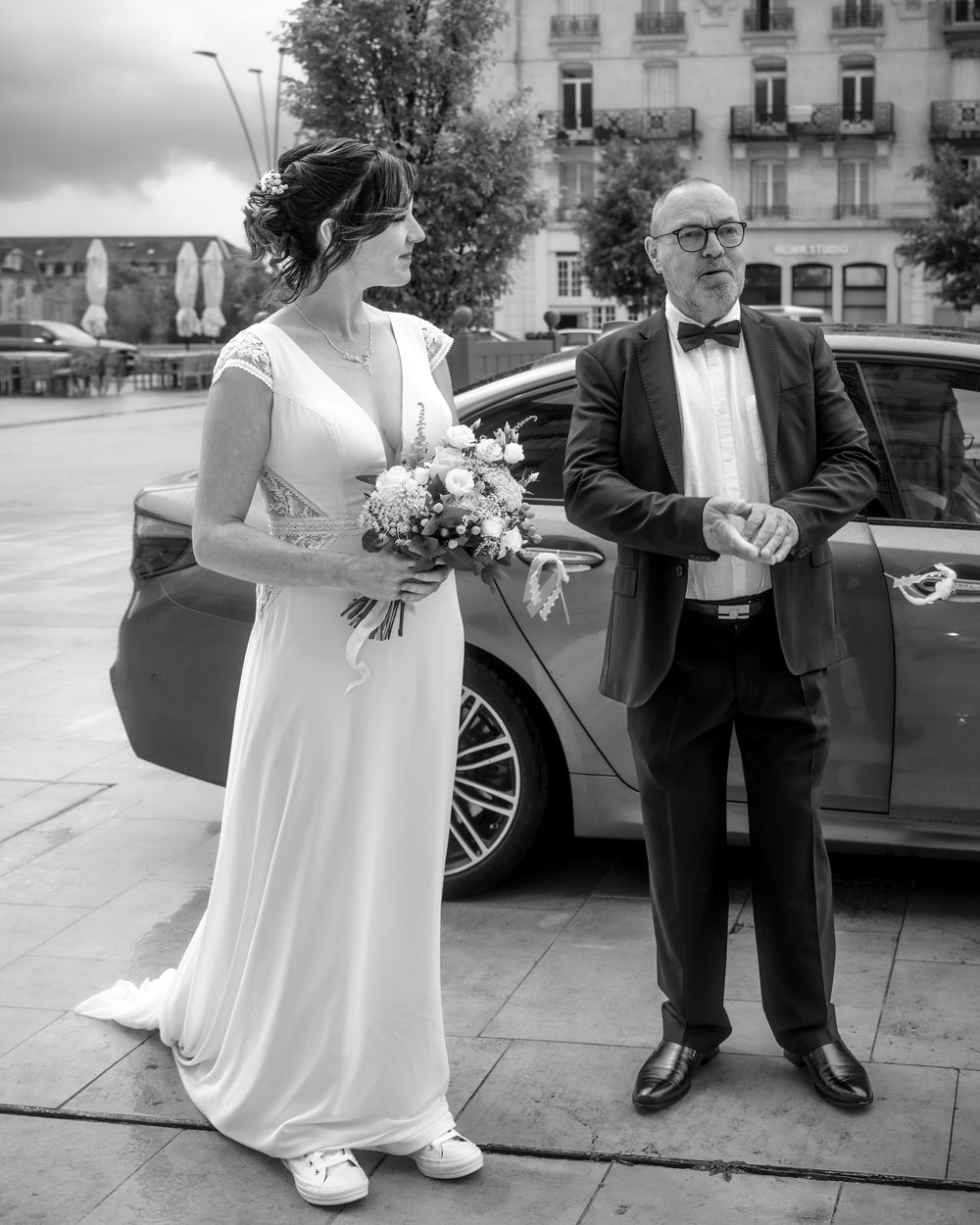 A sequence of black and white wedding photos showing the couple and guests arriving outside a building.